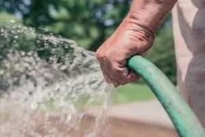 White skinned person holding green hose