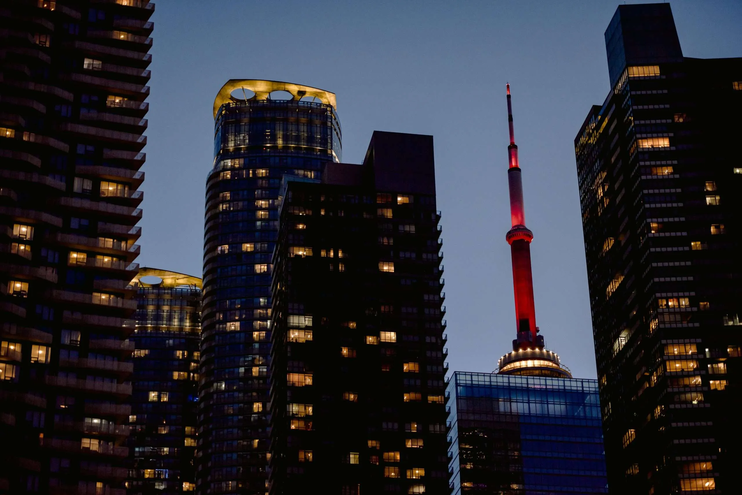 Condos downtown at night in Toronto with CN Tower in background condo trees